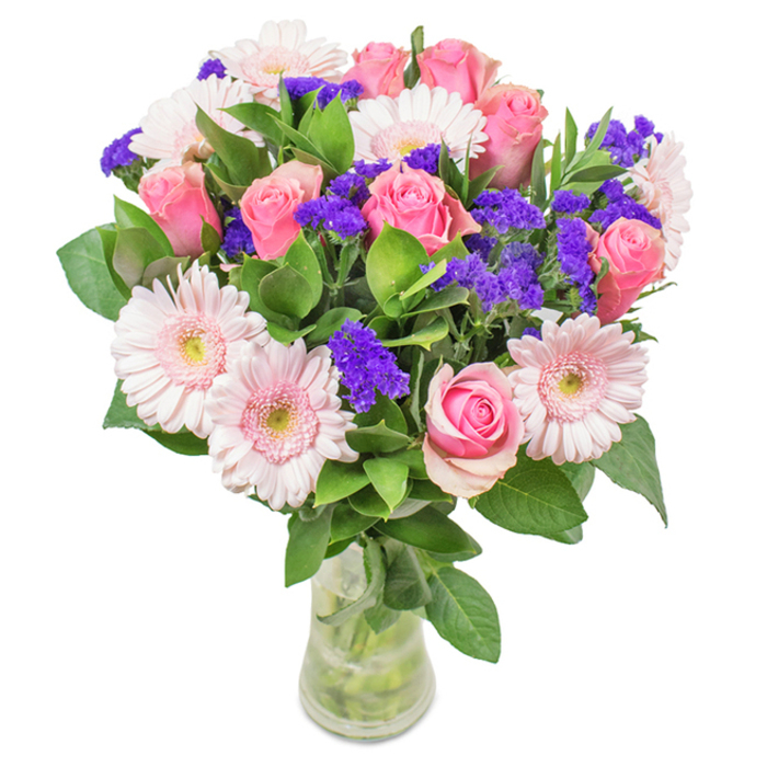 A beautifully structured bouquet from a Harpenden florist, poised in a transparent glass vase and set against a soft, white backdrop. The arrangement boasts around eight lush pink roses-some tight buds, others unfurling their satin petals in gentle spirals-paired with six pale pink gerbera daisies whose broad, multi-layered petals subtly fade to creamy centers. Pops of bright purple statice are woven through the bouquet, their crisp texture and hue adding depth and a contemporary edge, reminiscent of the lively colors at Harpenden Farmers' Market. Generous emerald greenery envelops the flowers, imparting a sense of freshness akin to the springtime foliage of Lydekker Park. Visible stems and sparkling water inside the slender vase evoke the handpicked charm of a local delivery. This bouquet is ideal for commemorating birthdays, anniversaries, or Mother's Day in Harpenden, and makes a graceful decorative accent for homes or offices, conveying affection and luminous celebration while championing expert craftsmanship found locally.